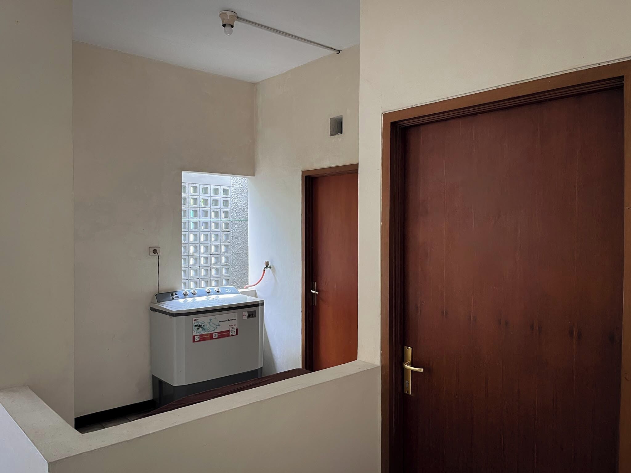 A hallway with a water heater, a window with a grid pattern, and a wooden door.
