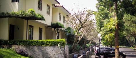A residential building with a stone wall, a paved driveway, and a parked car.