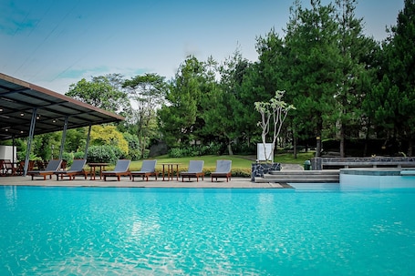Una piscina al aire libre, sillones reclinables de piscina