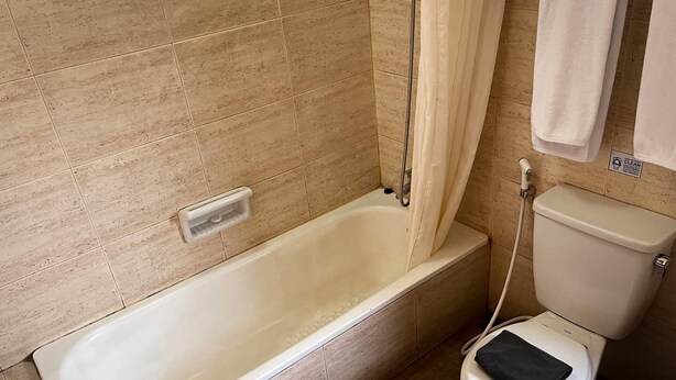 A bathroom with a bathtub, toilet, and a shower curtain. - Puri Setiabudhi Residence (Bandung)