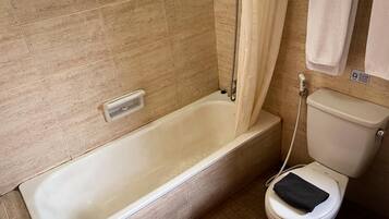 A bathroom with a bathtub, toilet, and a shower curtain.