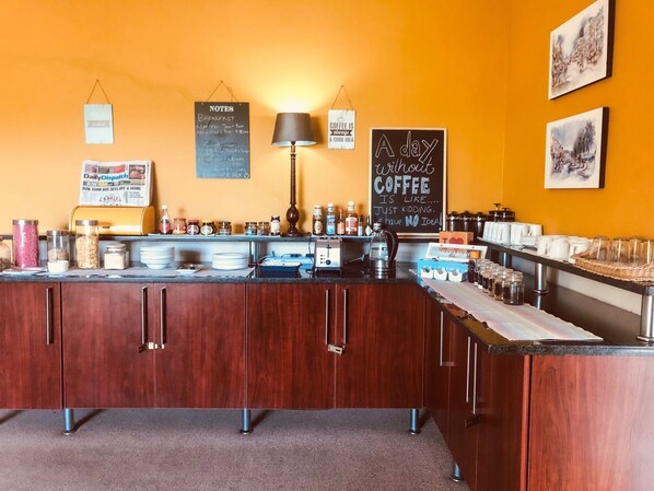 A café counter with a chalkboard menu, coffee station, and various jars of condiments. - Selborne Bed and Breakfast (East London)