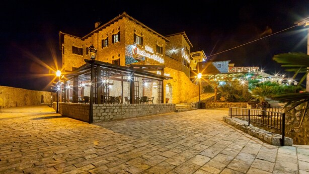 A historic building with a covered outdoor seating area and a stone staircase leading to a higher level. - Hotel Kulla e Balshajve (Ulcinj)