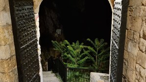 Un escalier en pierre menant à un intérieur sombre, flanqué de deux grandes portes richement décorées.