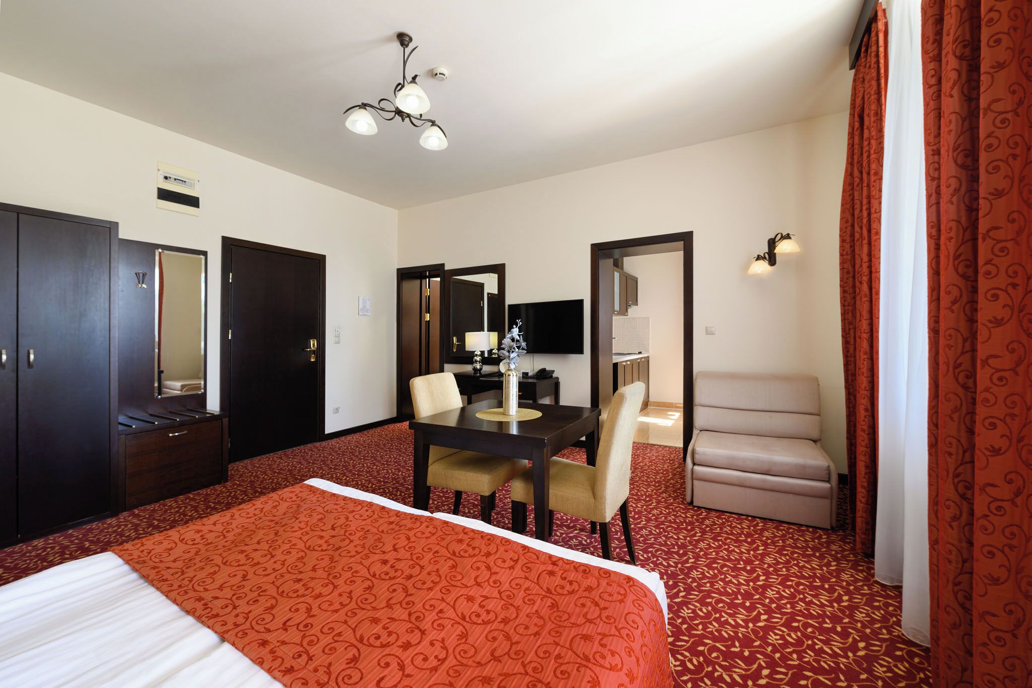Una habitación de hotel con una cama grande, un escritorio con sillas, un sofá y un televisor.
