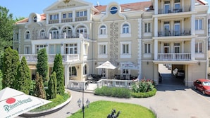 A large, multi-story hotel with a classic architectural style, featuring balconies, a central courtyard, and outdoor seating areas. - Hotel Aurum (Hajduszoboszlo)