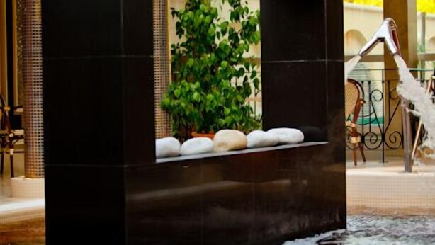 A modern indoor water feature with a stone basin and a fountain. - Hotel Aurum (Hajduszoboszlo)
