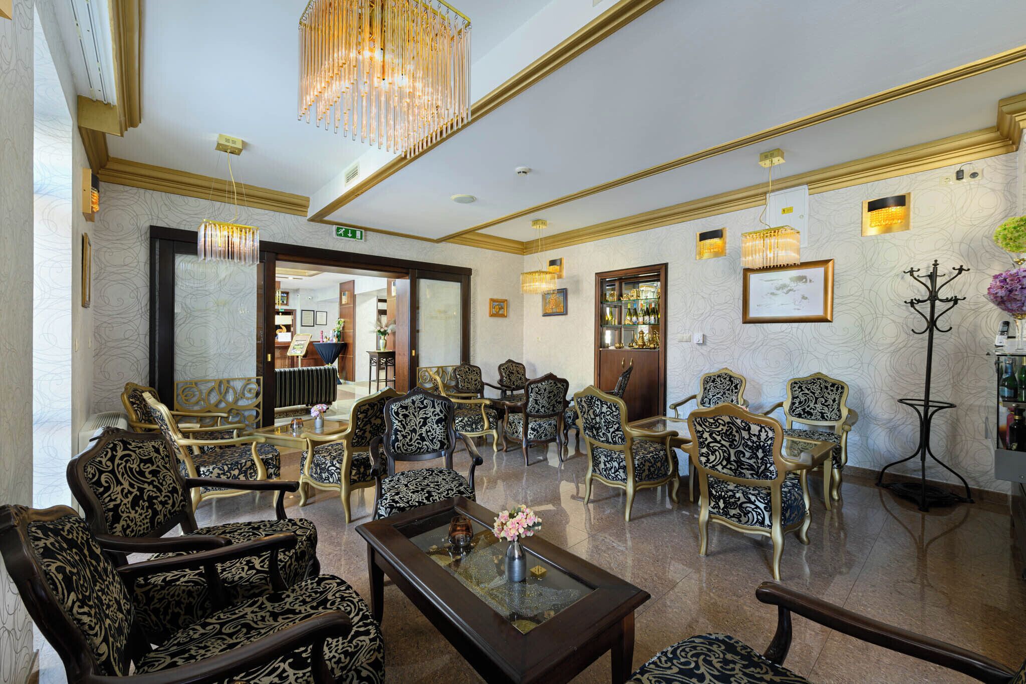 A spacious lobby with ornate chairs, a glass coffee table, and a chandelier.