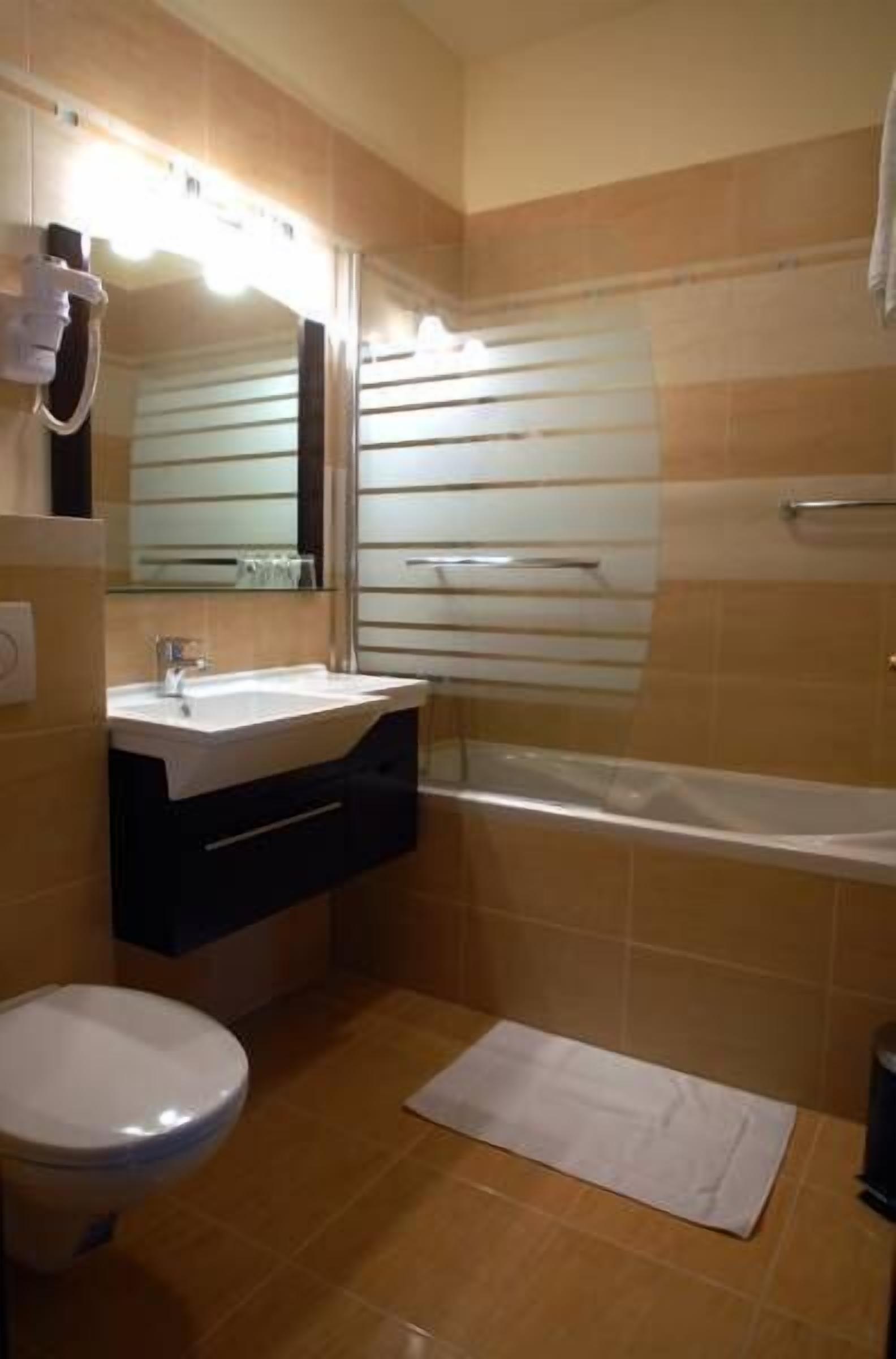 Un baño con lavamanos, espejo e inodoro.