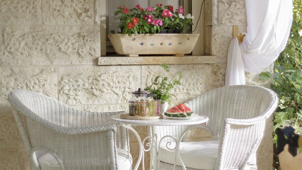 Une table en osier avec des chaises, une plante en pot, une tranche de pastèque et une petite fenêtre décorée de fleurs.