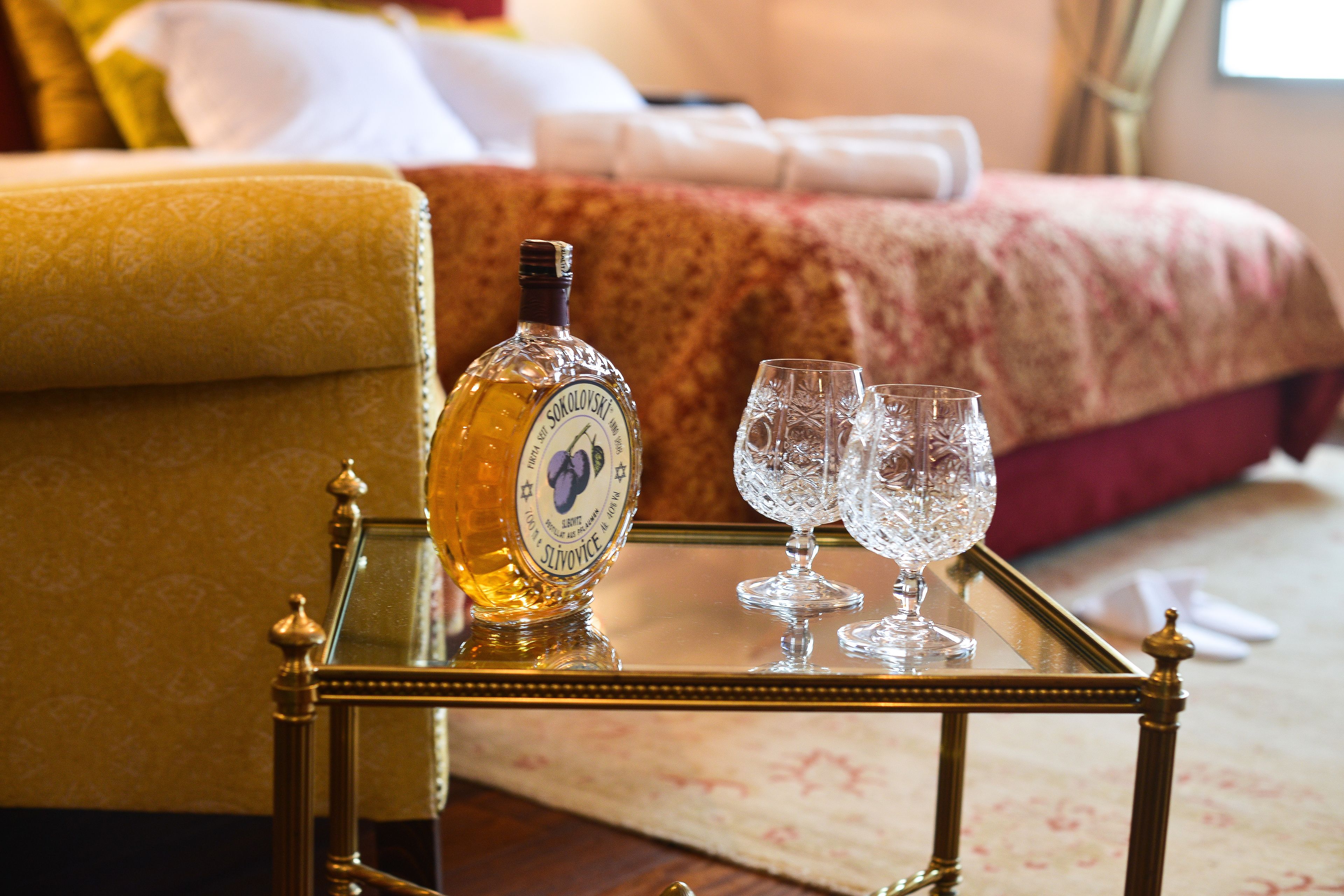 A bottle of liquor and two glasses on a tray in a hotel room.