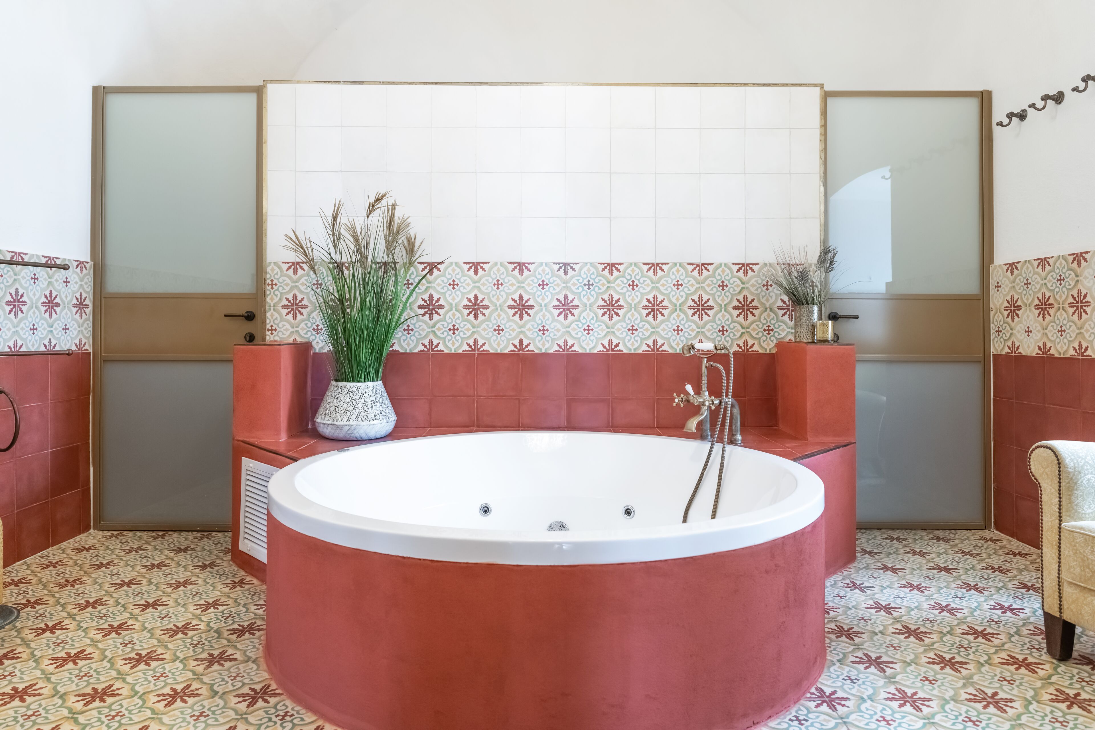 A bathroom with a large freestanding bathtub, a mirror, and patterned tiles.