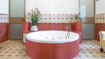 A bathroom with a large freestanding bathtub, a mirror, and patterned tiles.