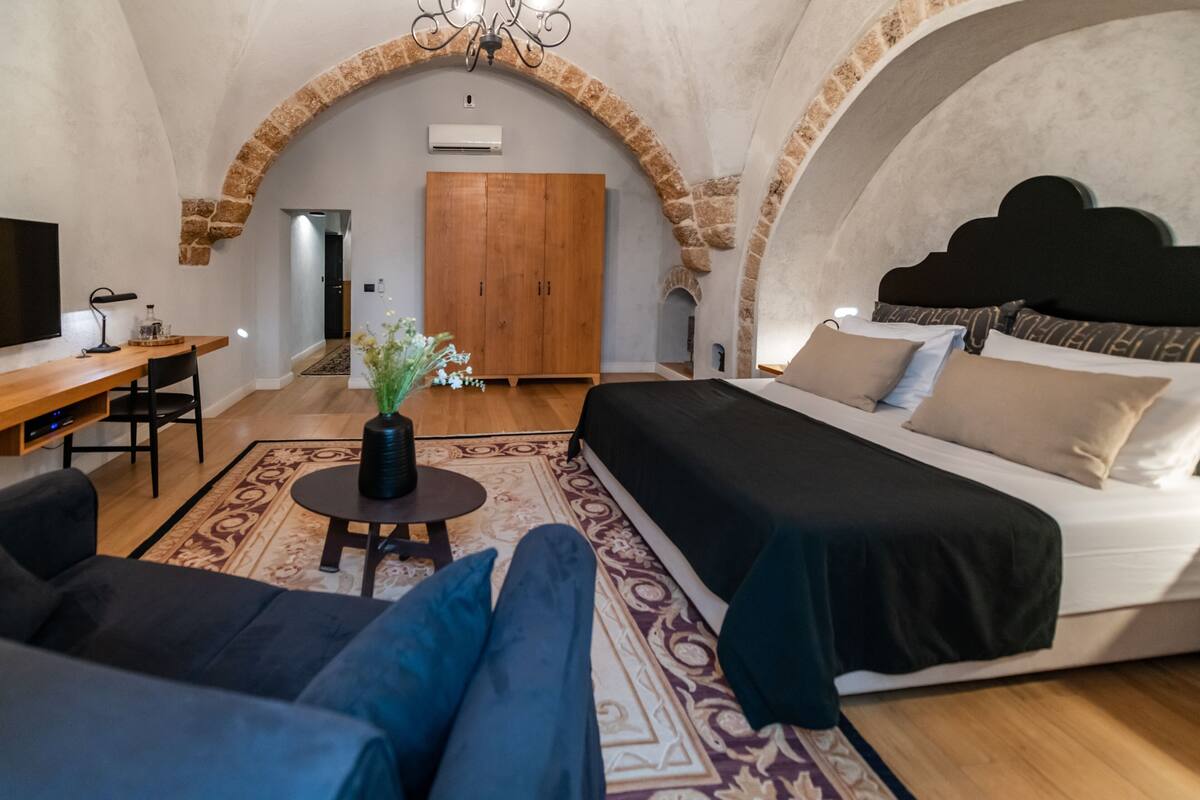 Ein Zimmer mit Bett, Sofa, Schreibtisch und Fernseher.