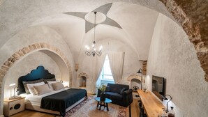 A bedroom with a bed, a desk, a chair, and a chandelier.