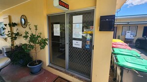 Un immeuble de bureaux avec une enseigne indiquant « BUREAUX », un panneau « PAS DE CHAMBRES LIBRES » et un paillasson « BIENVENUE ».