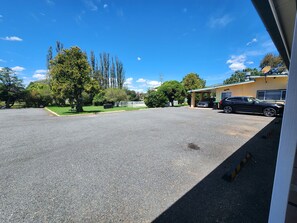Ein Parkplatz mit einem Gebäude, Bäumen und blauem Himmel.