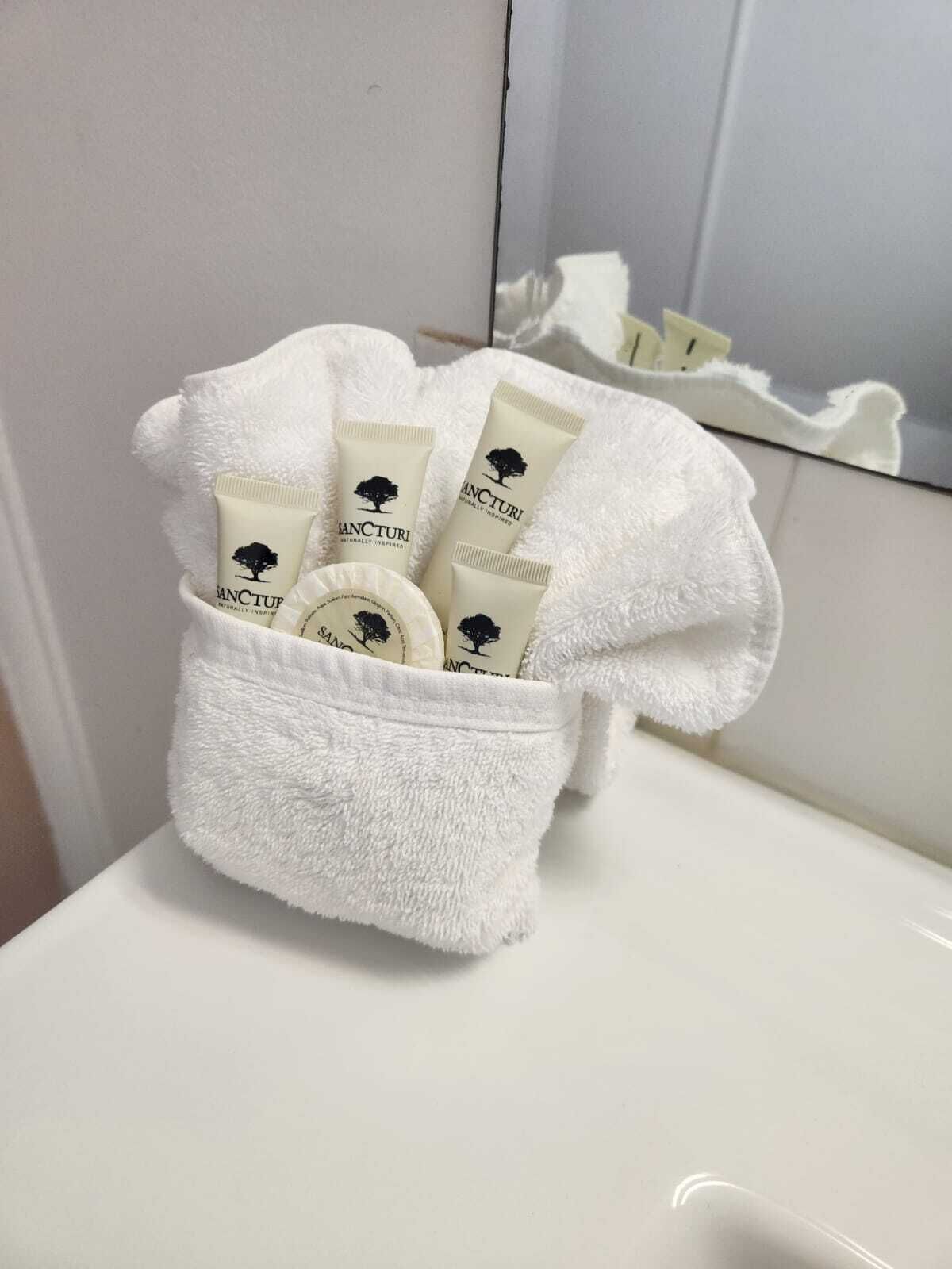 Un baño con una toalla blanca colgada en un perchero, sosteniendo varios tubos de crema.