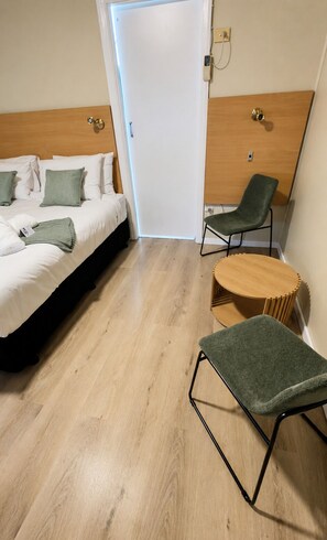 A hotel room with a bed, two chairs, a small wooden table, and a white door. - Murrurundi Motel (Murrurundi)
