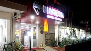 Exterior de l'Hotel Diamond Alanya, amb façana de pedra, un tendal vermell i una escala que condueix a l'entrada.