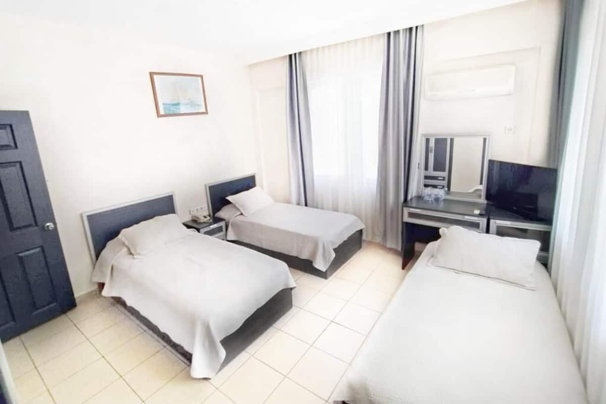 A hotel room with two single beds, a desk with a computer, and a television.
