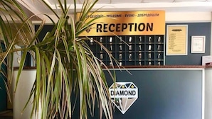 Zona de recepció amb un paviment a escac i llambordes, una taula d'informació i un senyal que diu 'RECEPTION'.