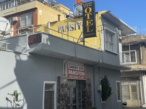 Un bâtiment avec une enseigne indiquant « ERSOY EFE PANSIYON HOTEL » et une autre indiquant « ERSOY EFE PANSIYON, douche, climatisation, télévision, Wi-Fi ».