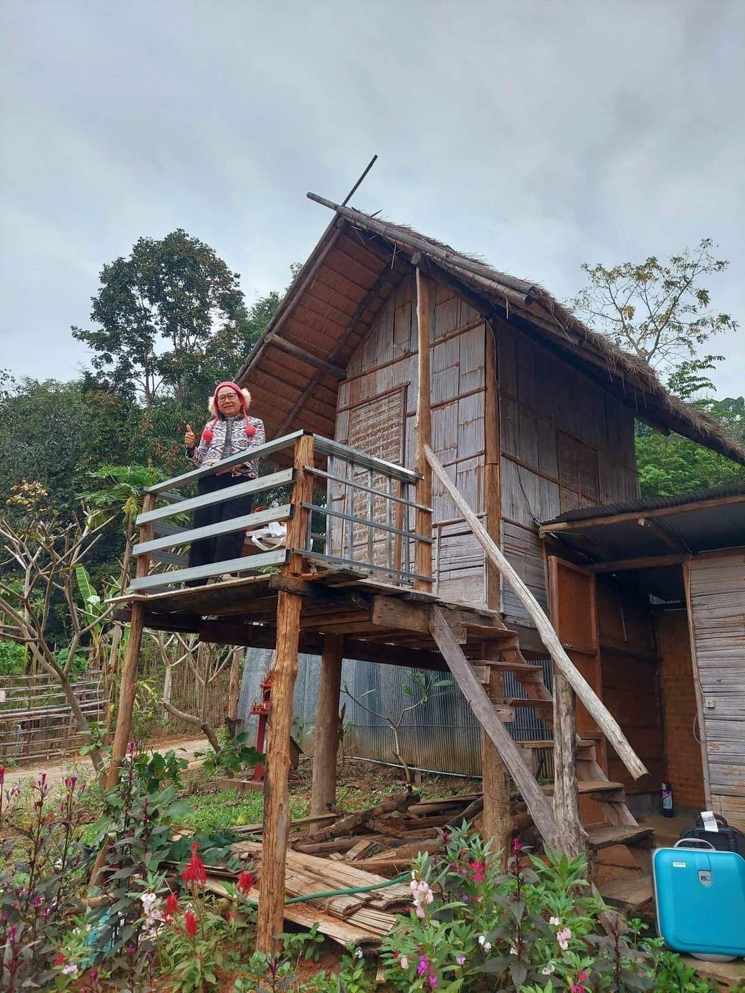 A wooden house with a balcony, surrounded by greenery.