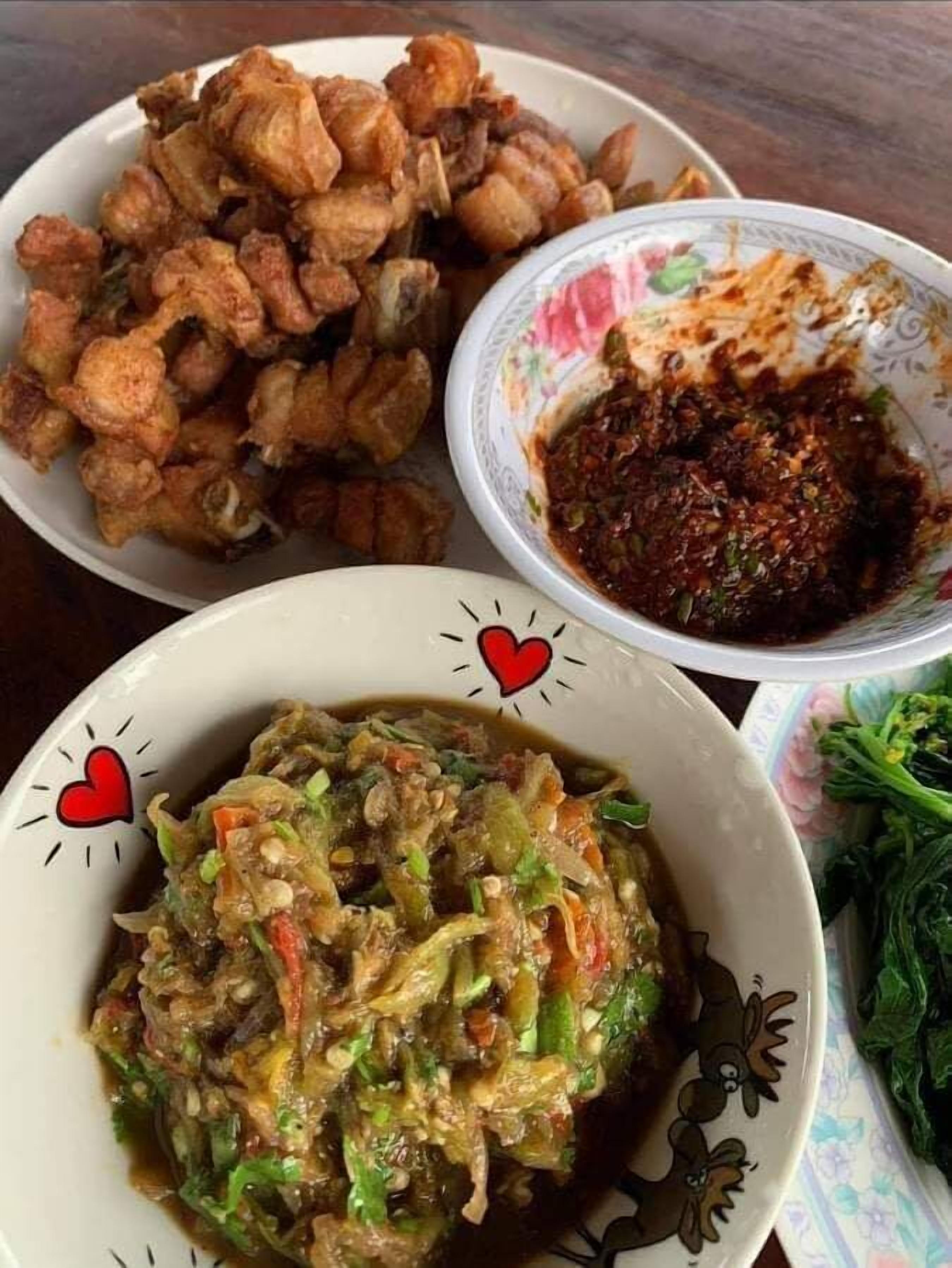 Una mesa con tres platos: pollo frito, salsa picante y un guiso de verduras.
