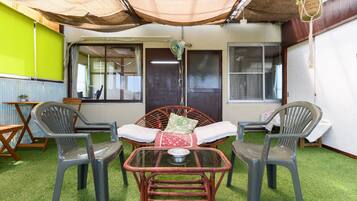 Un patio con mesa y sillas, una planta colgante y una puerta.