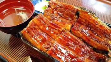A tray of glazed fish slices, a small bowl of soup, and a small dish of pickled vegetables.