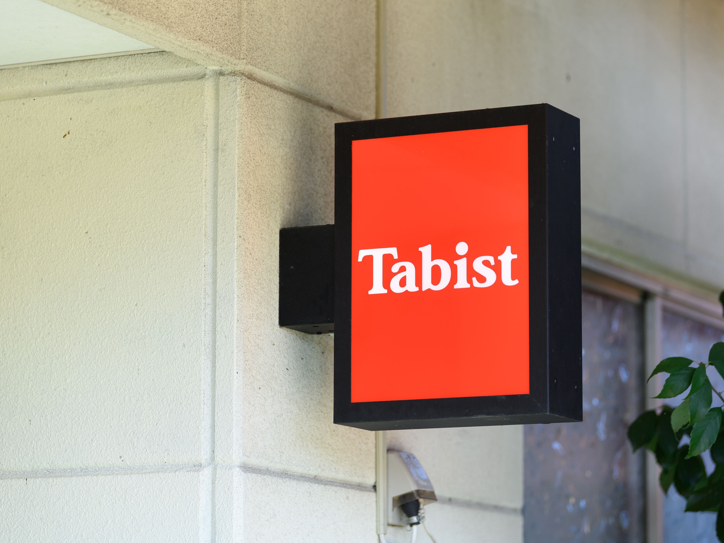 Ein Schild mit dem Wort 'Tabist' auf rotem Grund.