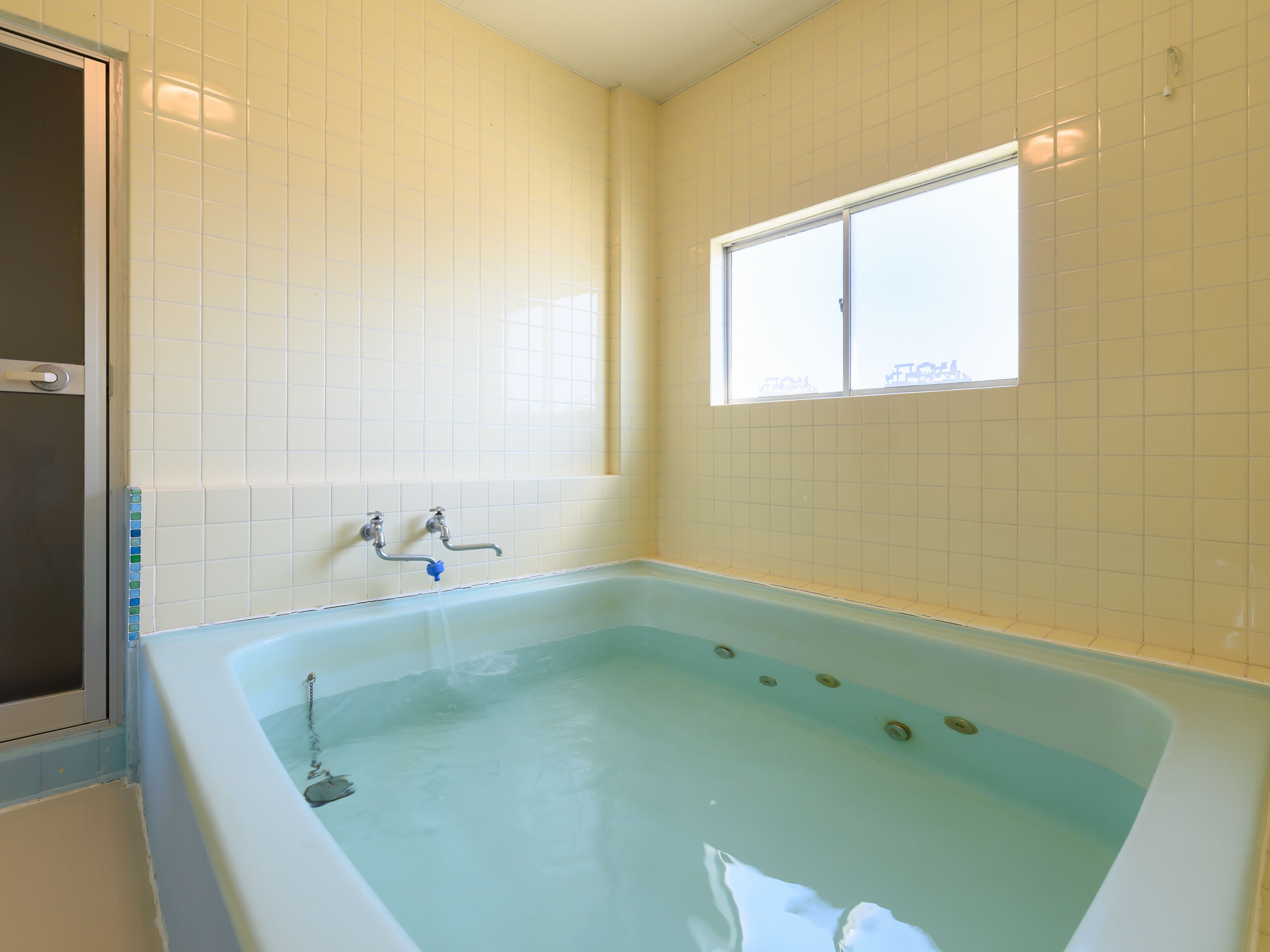 A bathroom with a bathtub, a window, and a shower area.