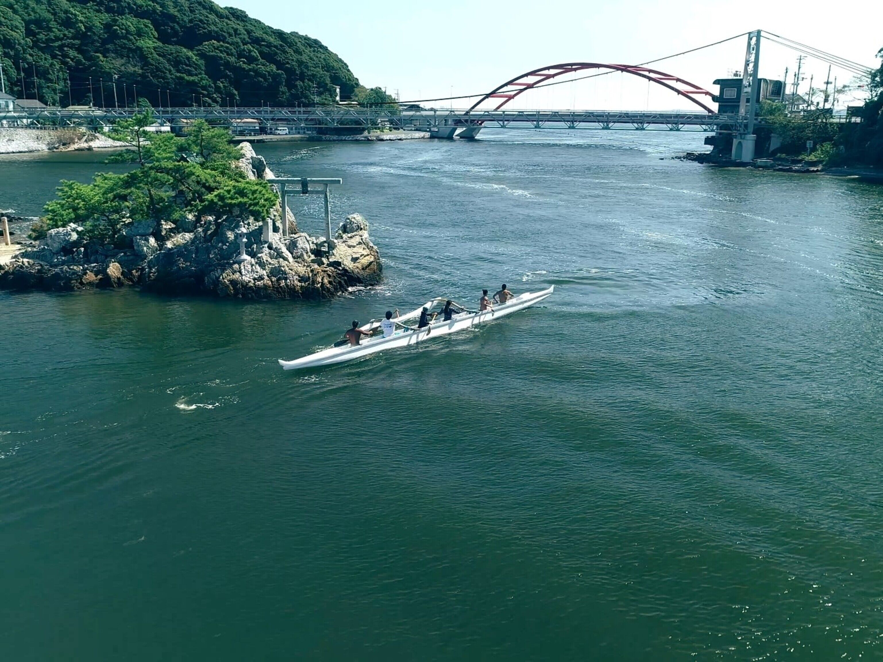 Une rivière avec un pont et une île rocheuse.