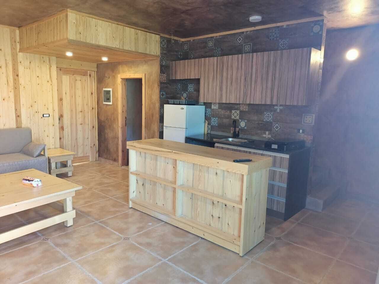 A wooden interior with a kitchen area, a sofa, and a small table.
