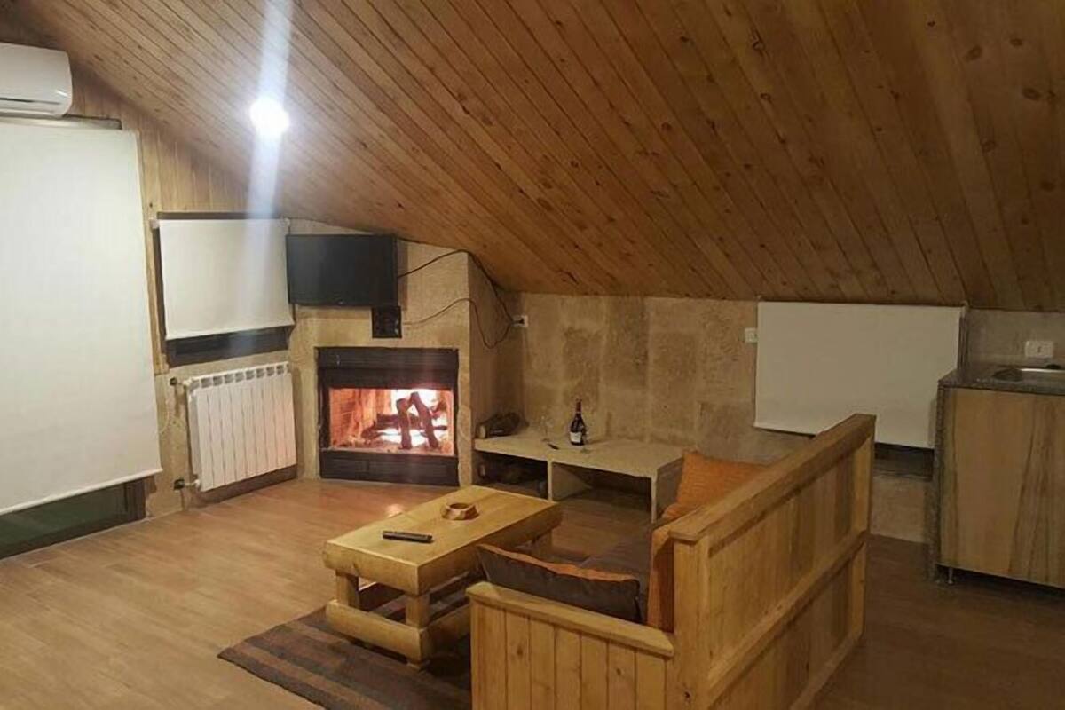 Acogedor dormitorio en ático con chimenea, muebles de madera y televisión.