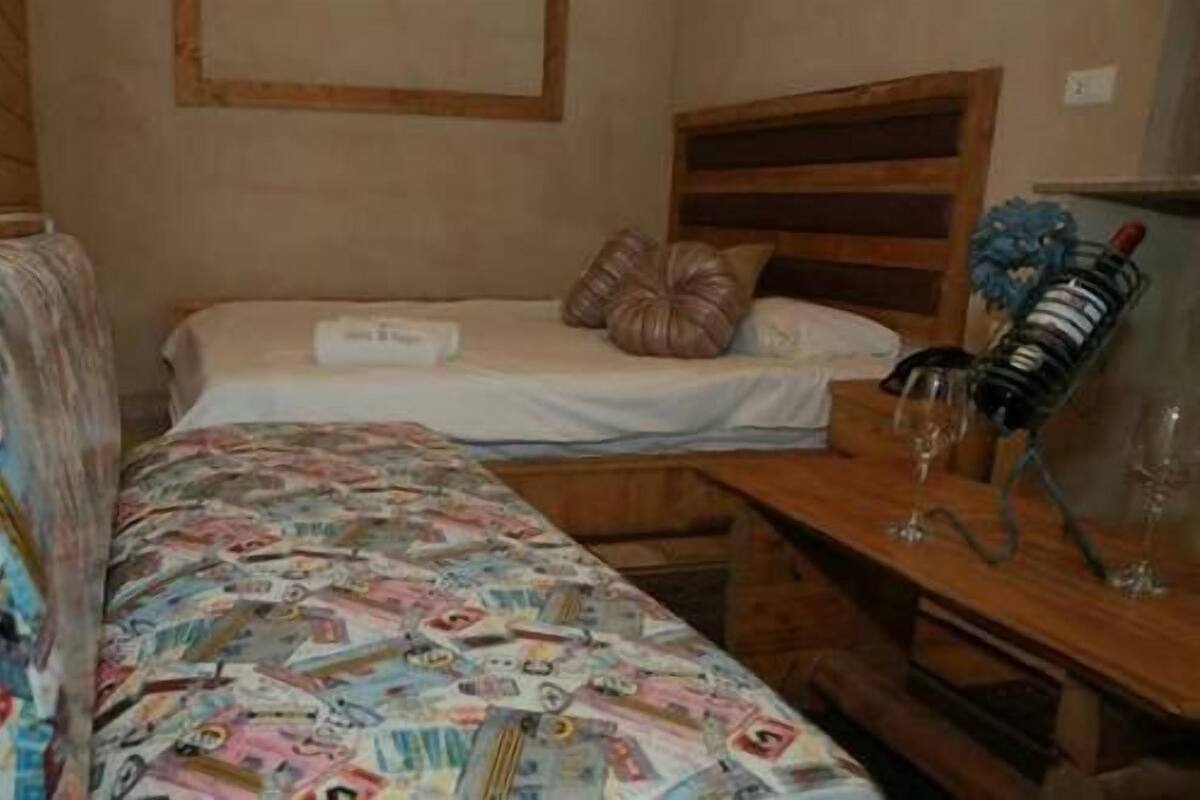 Una habitación pequeña con cama individual, mesita de noche y una silla.