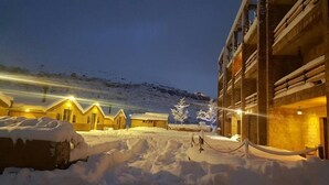A snow-covered outdoor area with wooden cabins and a building with balconies. - Villetta Di Faraya (Faraya)
