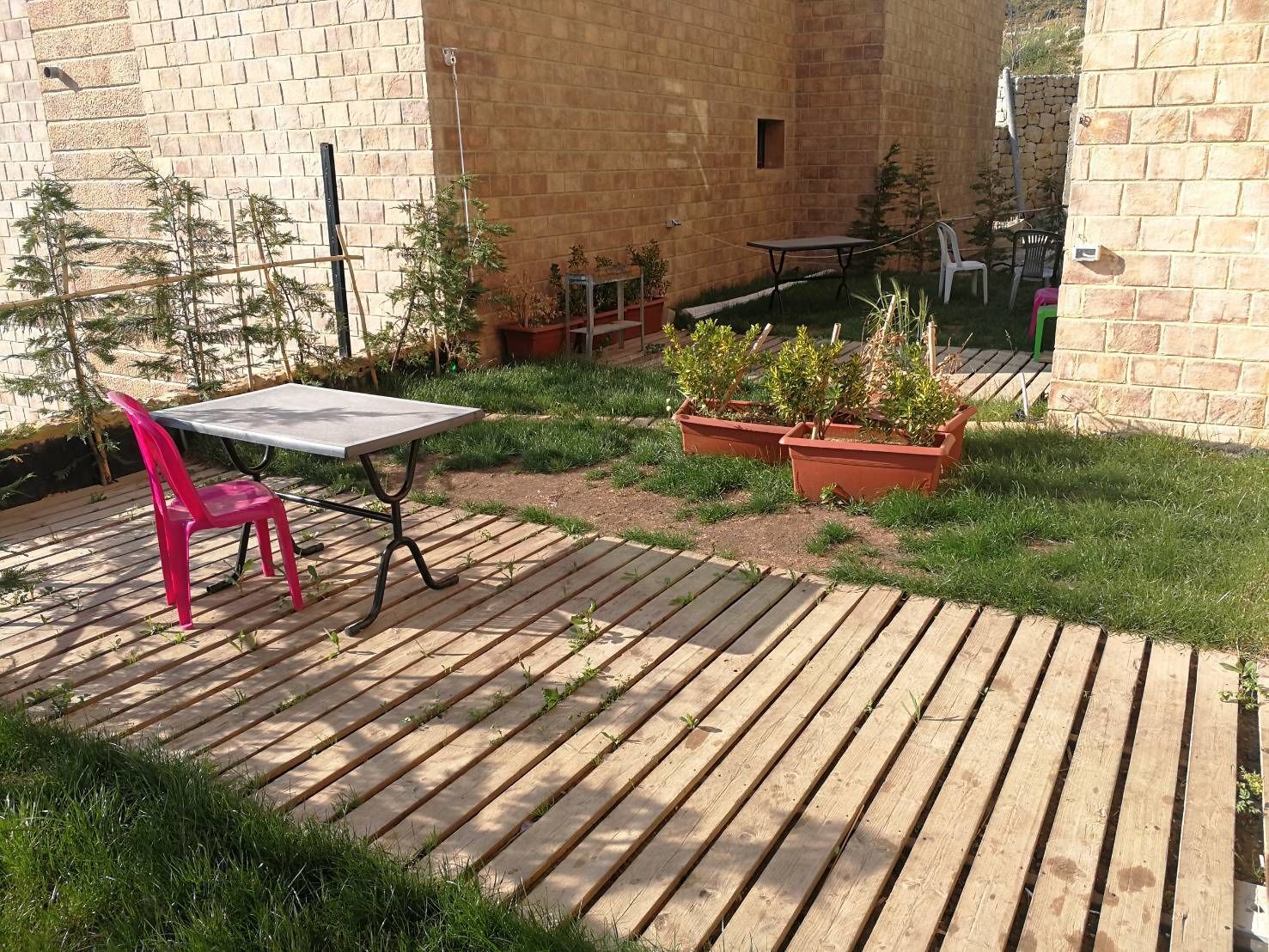 A patio area with a table and chairs, surrounded by a brick wall and potted plants.