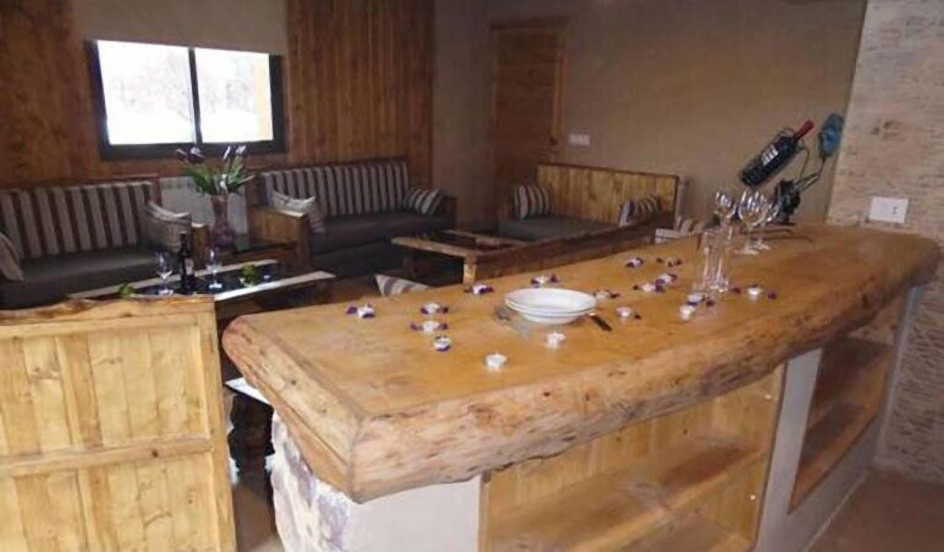 A rustic wooden bar area with a sofa and a dining table set for a meal.