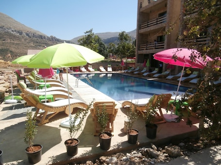 Una piscina al aire libre de temporada, sombrillas