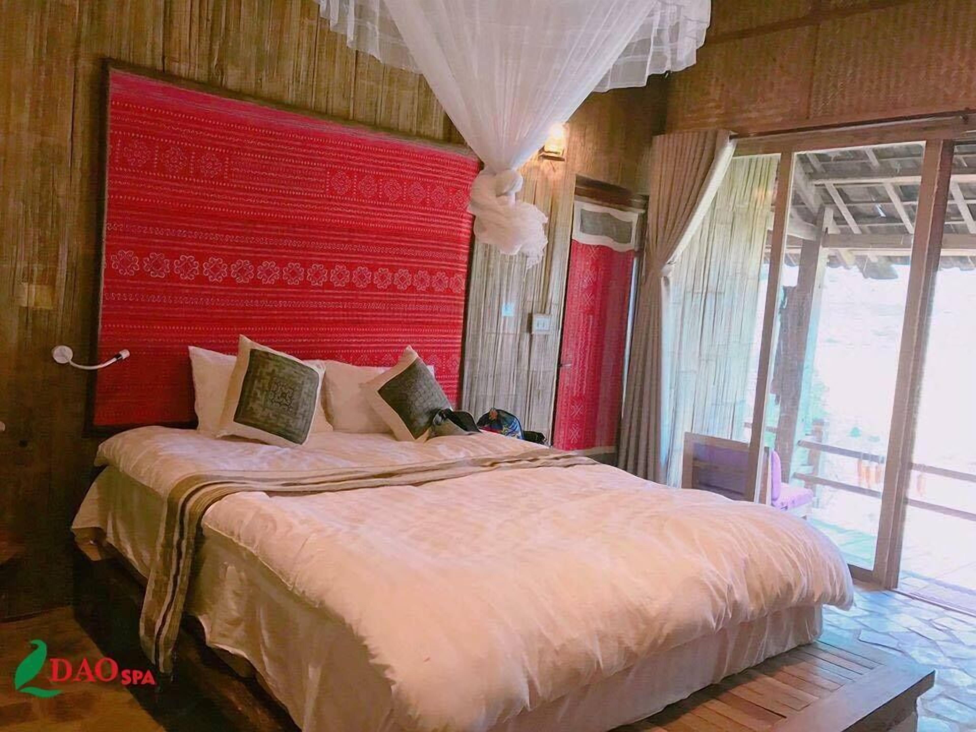 Um quarto espaçoso com uma cama grande, cabeceira vermelha e dossel.