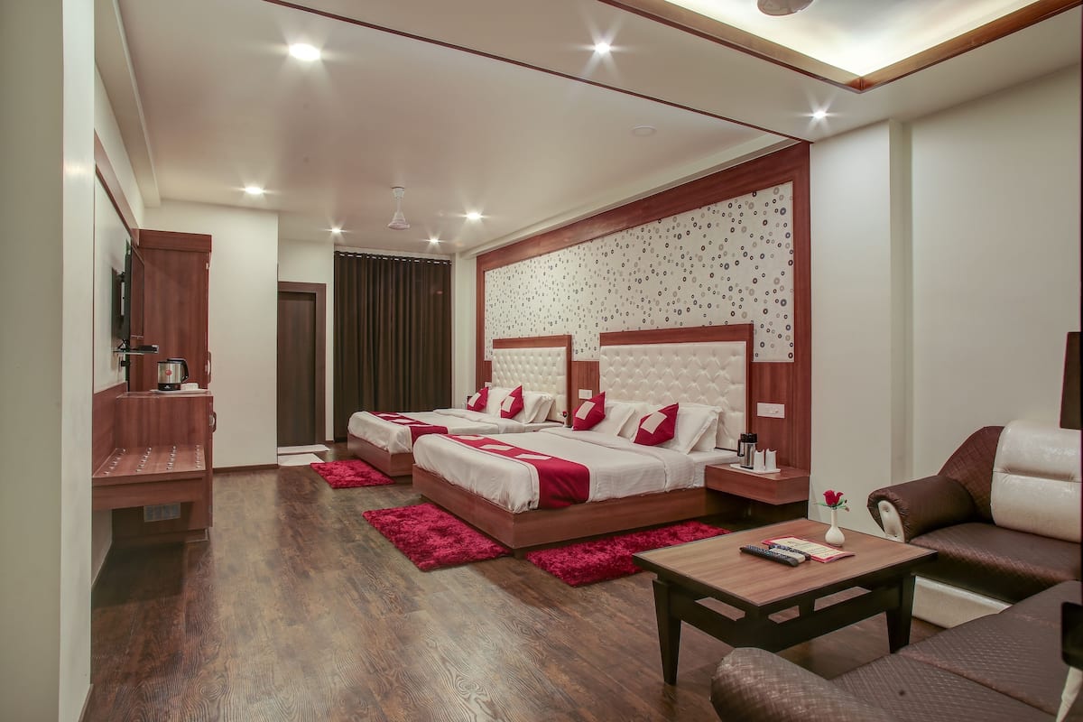 A modern bedroom with two beds, a wooden bench, a coffee table, and a sofa.