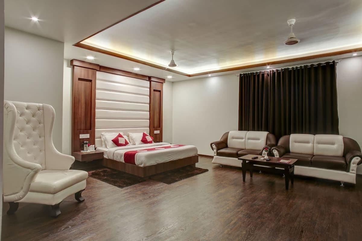 A bedroom with a bed, a sofa, a chair, and a ceiling fan.