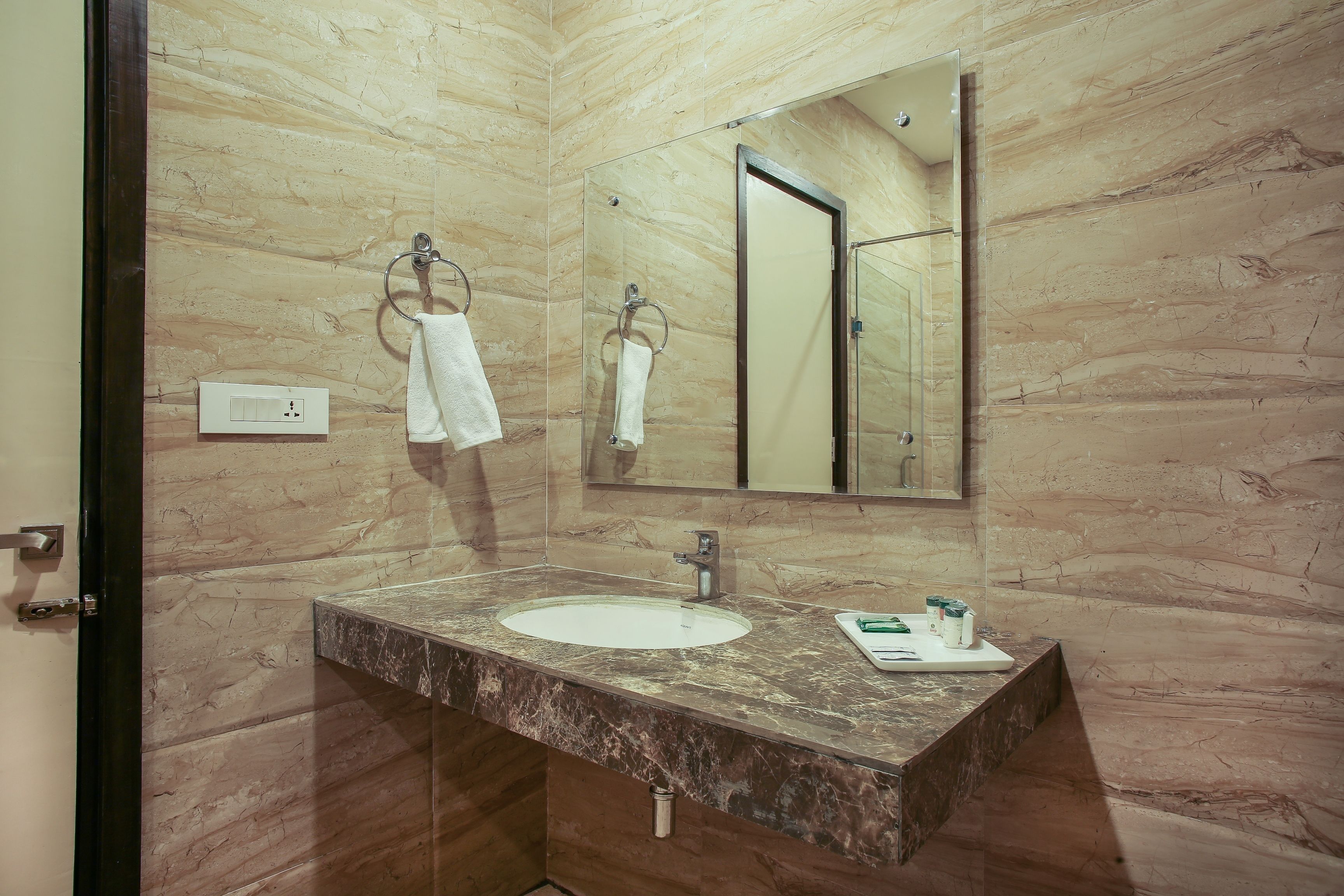 A bathroom with a marble sink, a glass shower enclosure, and a large mirror.