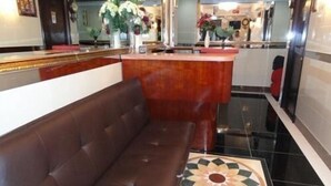 Um lobby com um sofá marrom, uma mesa de recepção e um padrão decorativo no chão.