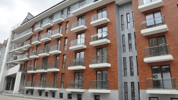 A multi-story building with balconies, large windows, and a mix of brick and concrete facades.