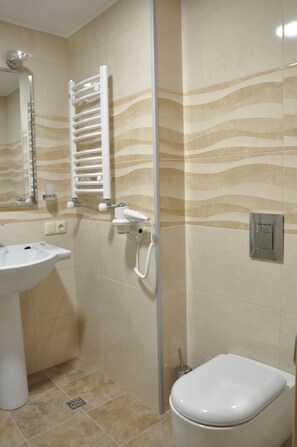 Une salle de bain équipée d’un lavabo, de toilettes, d’un porte-serviettes et d’un miroir.