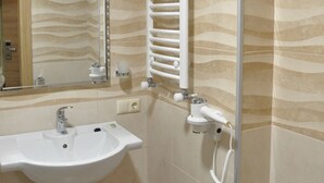 A bathroom with a sink, mirror, towel rack, and shower.