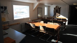 A conference room with a large table, chairs, a whiteboard, and a window with a view of a building. - Old Camp (Kangerlussuaq)